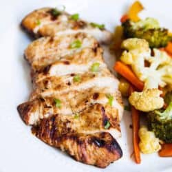 sliced grilled chicken on a plate with veggies