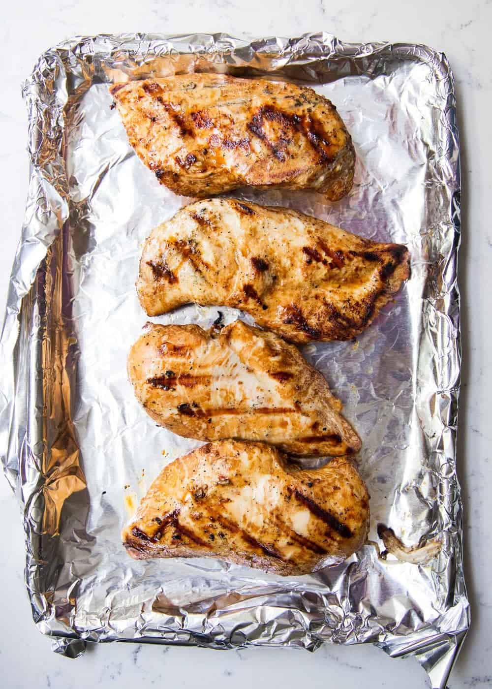 Grilled chicken on baking sheet.