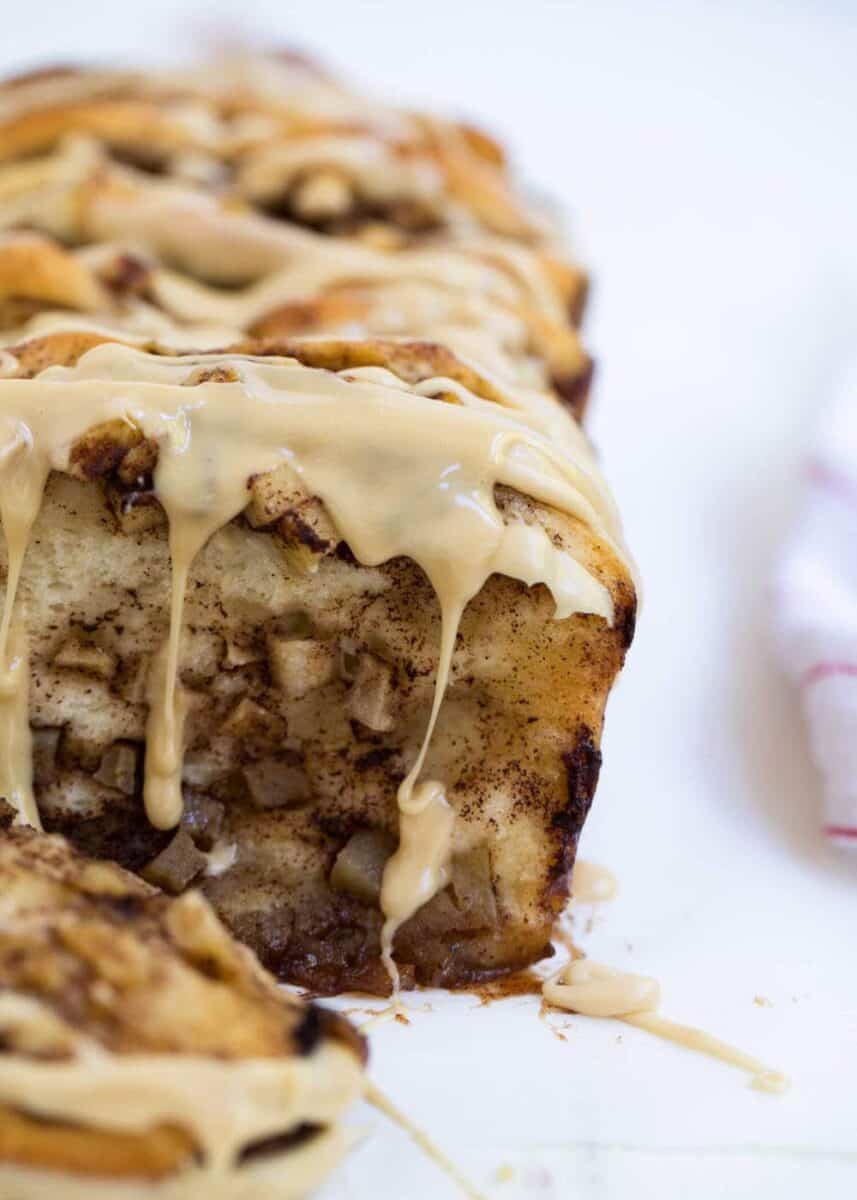 loaf of cinnamon apple pull apart bread with caramel icing dripping over sides 