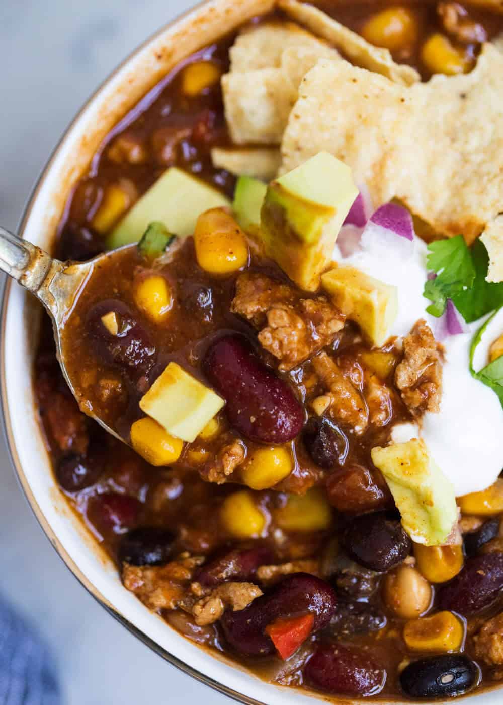 Bowl of healthy turkey chili with toppings and a spoon.