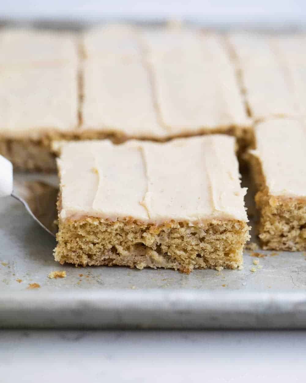 Slices of frosted banana bars on a baking sheet.