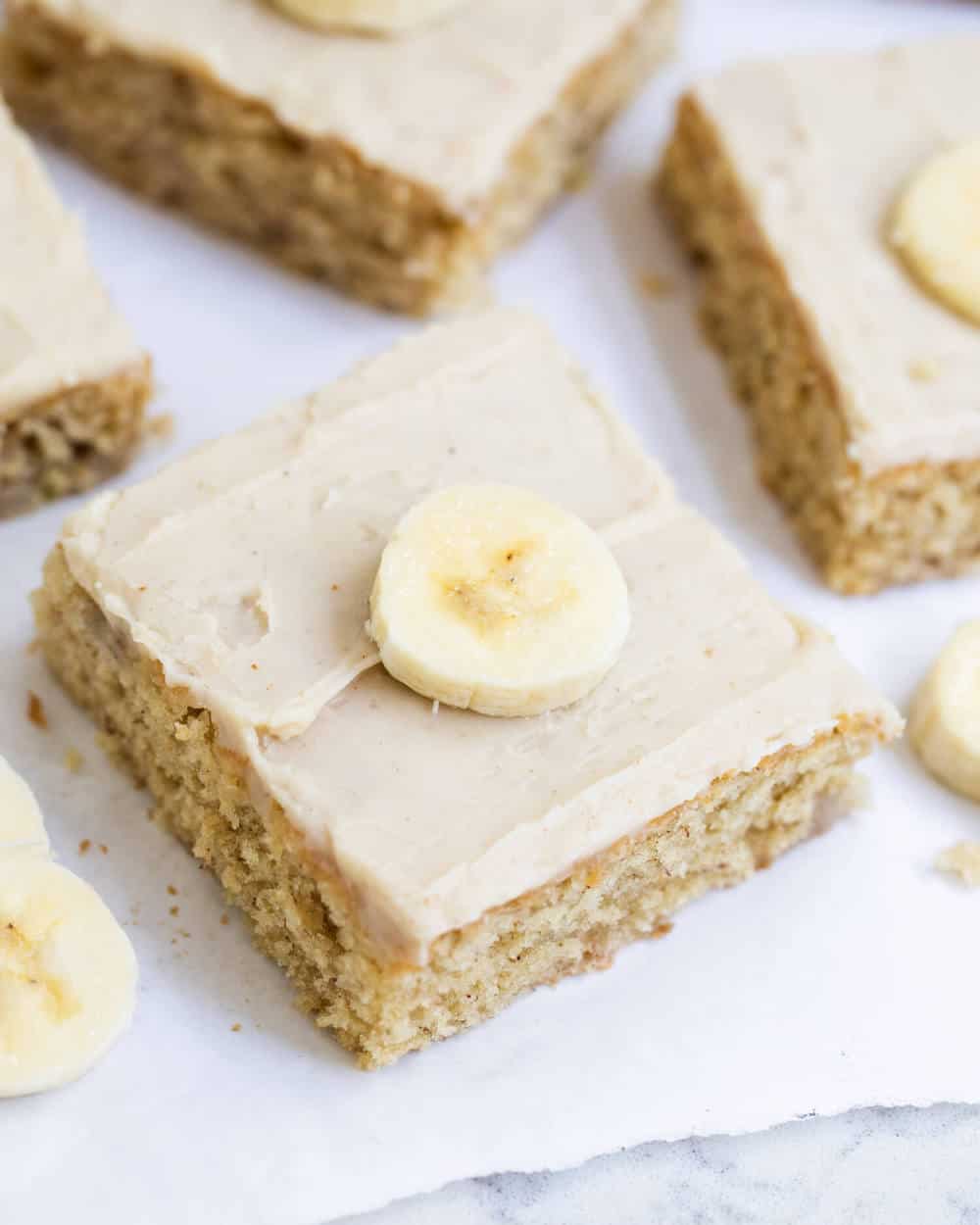 Banana bars with brown sugar frosting and banana slice on top.