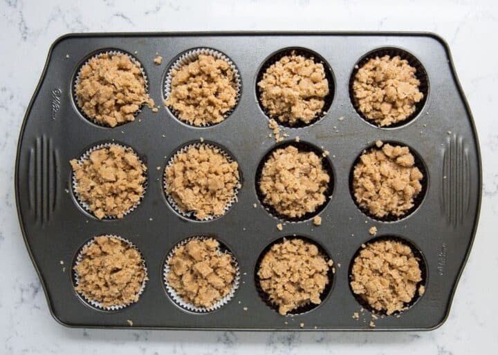 These moist pumpkin crumb muffins are made with cinnamon, applesauce and pumpkin spice. Bonus points for a mouthwatering (and slightly addictive) crumb topping. They are the perfect grab-n-go snack! pumpkin streusel muffins in pan