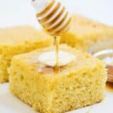 drizzling honey on top of a piece of sweet cornbread