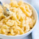 dipping a fork into a bowl of creamy macaroni and cheese