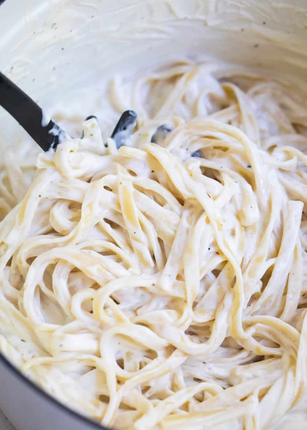 This cream cheese alfredo sauce is smooth, creamy and has the perfect texture and flavor! Simple to whip up and always a family favorite. pasta fork scooping cream cheese alfredo