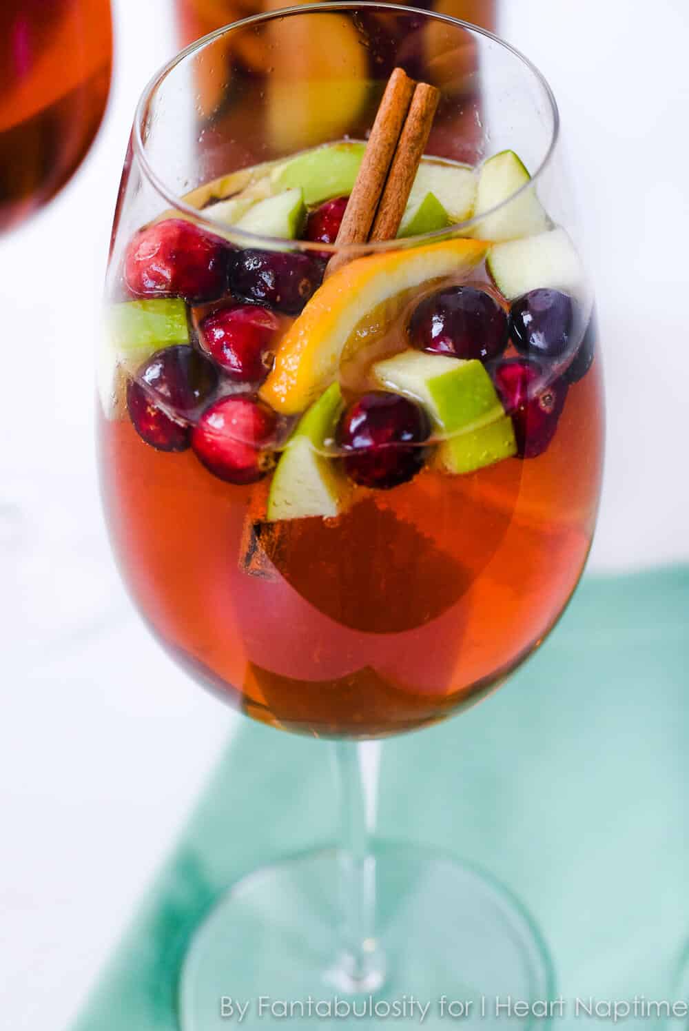 christmas sangria in a wine glass with fruit and cinnamon sticks on top 