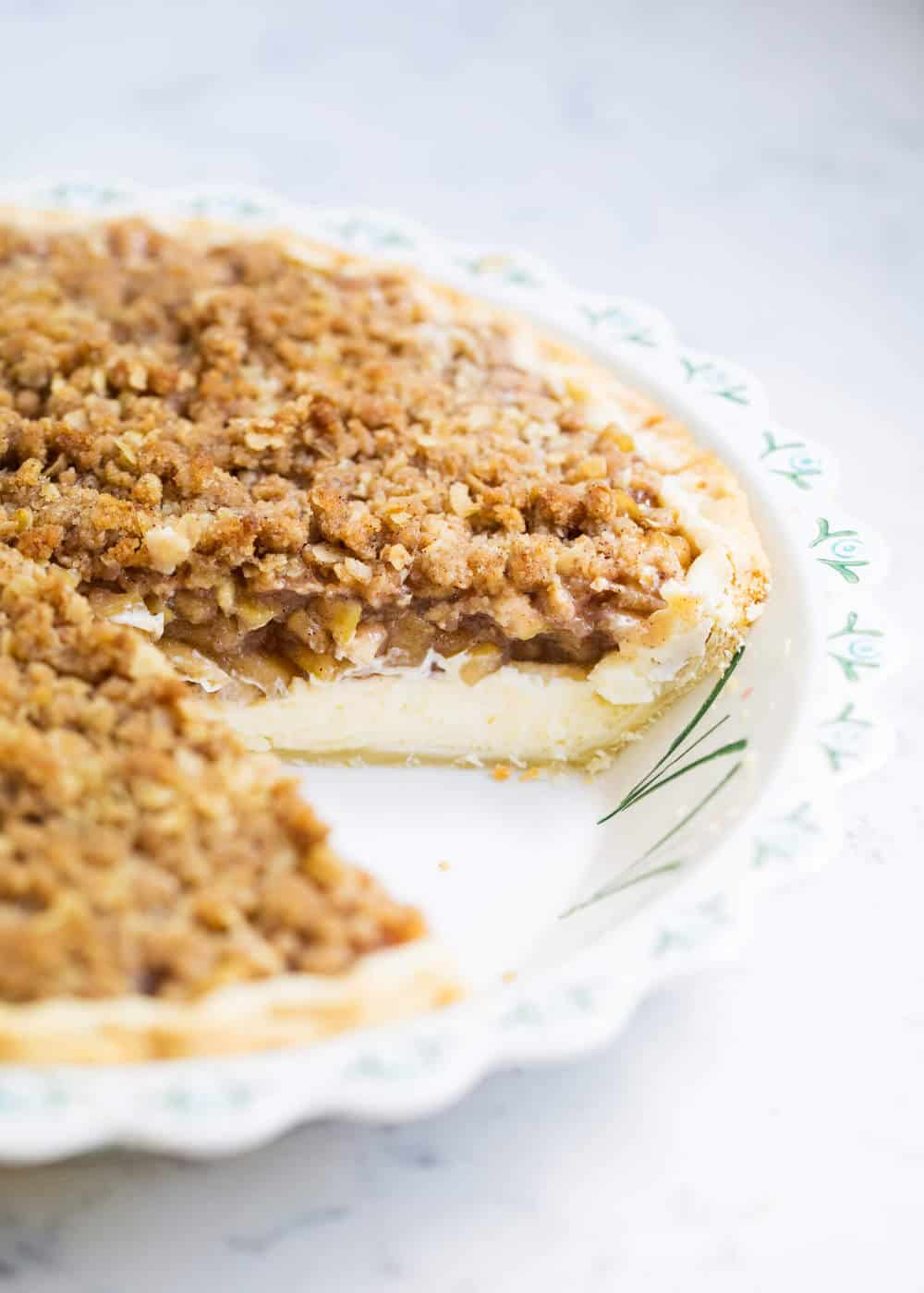 Apple cheesecake pie in pie pan with a slice taken out.