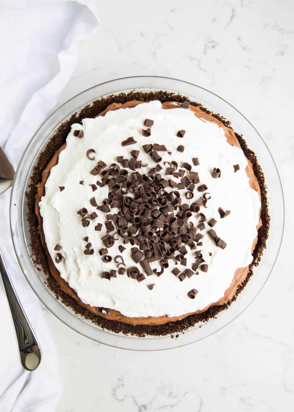 The ultimate chocolate silk pie made with a chocolate crust, silky smooth chocolate filling and topped with homemade whipped cream and chocolate shavings. This dessert is a chocolate lovers dream! French silk pie in pan.