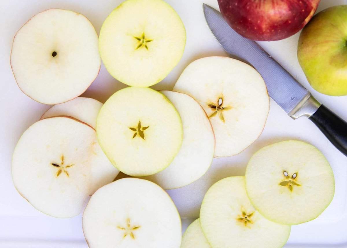 Slicing apples into rounds on cutting board.