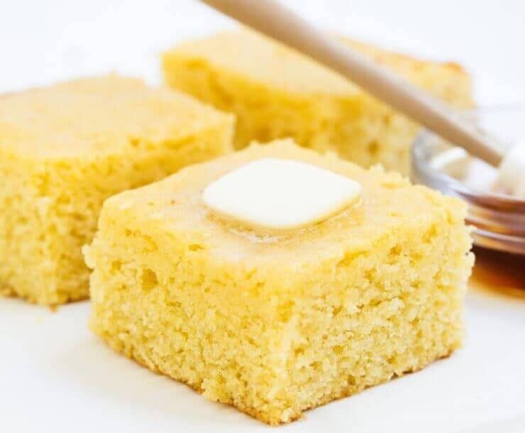 Piece of sweet cornbread with butter and honey.