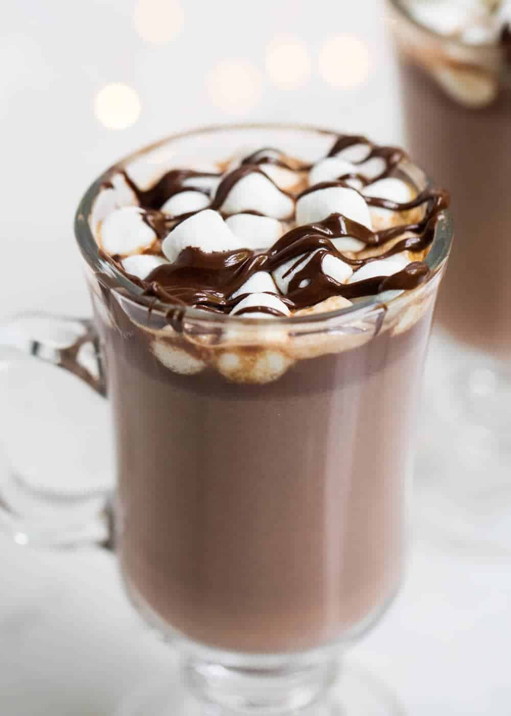 Hot chocolate in a glass cup with marshmallows and chocolate on top. 