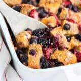 scooping out berry overnight french toast with a wooden spoon