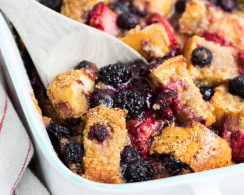 scooping out berry overnight french toast with a wooden spoon