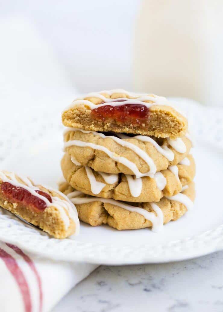 Stacked peanut butter and jelly cookies on white plate
