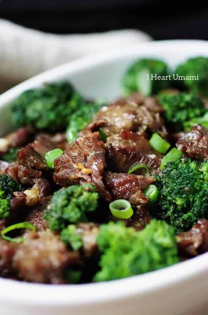 a close up of beef and broccoli with scallions 