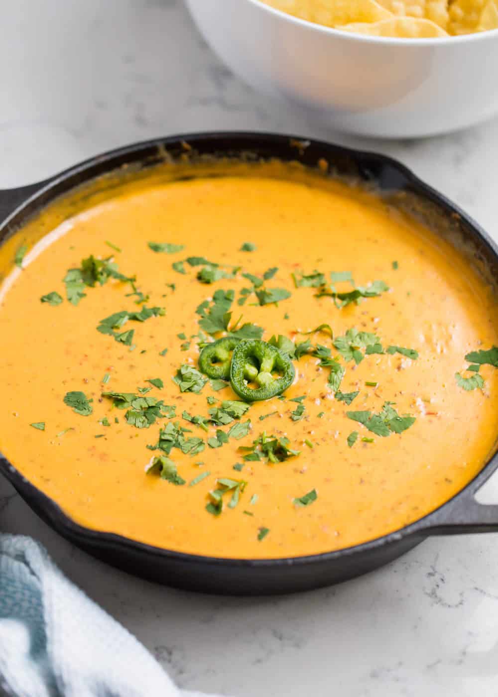 Skillet queso with cilantro and jalapeno on top.