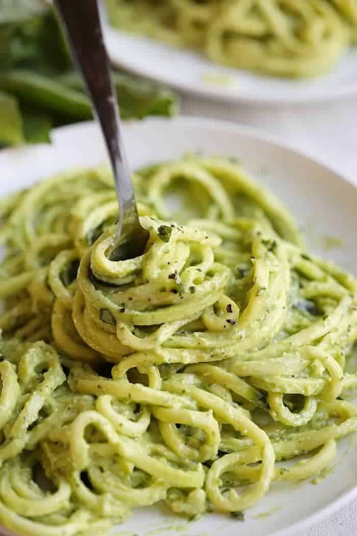 twisting up avocado pesto zucchini noodles with a fork 
