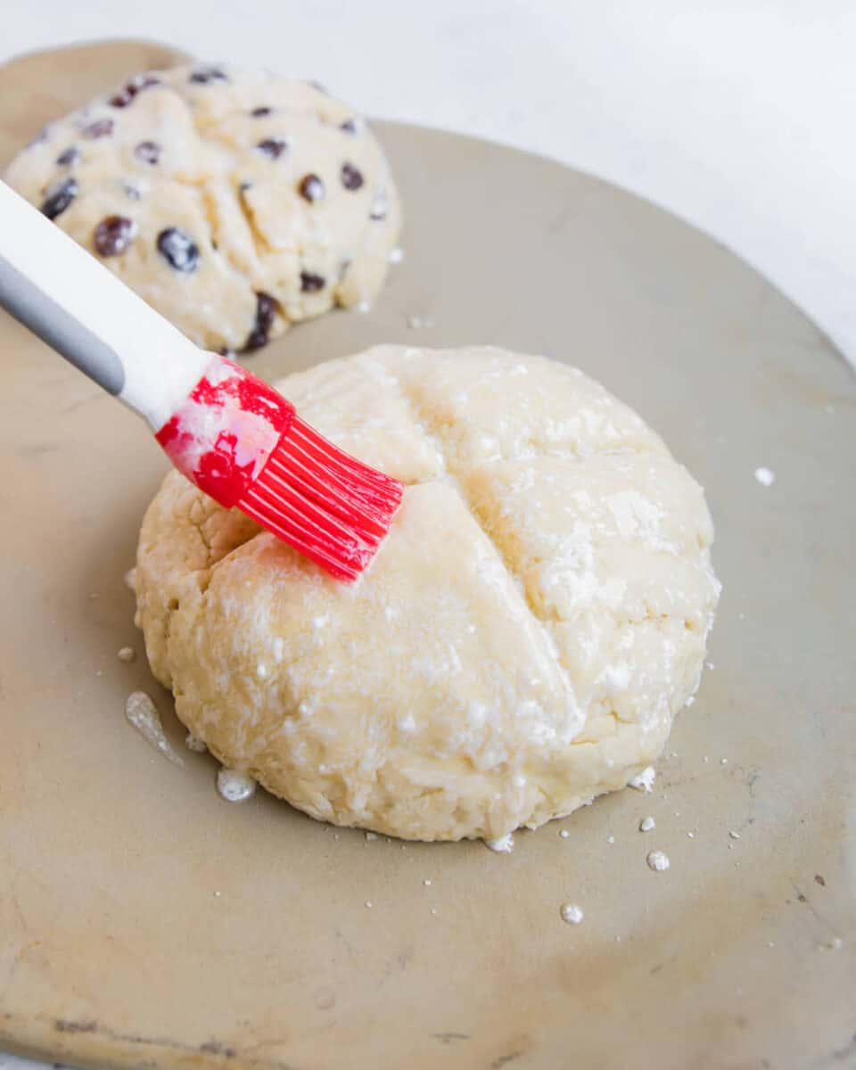 Brushing buttermilk on top of Irish soda bread before baking.