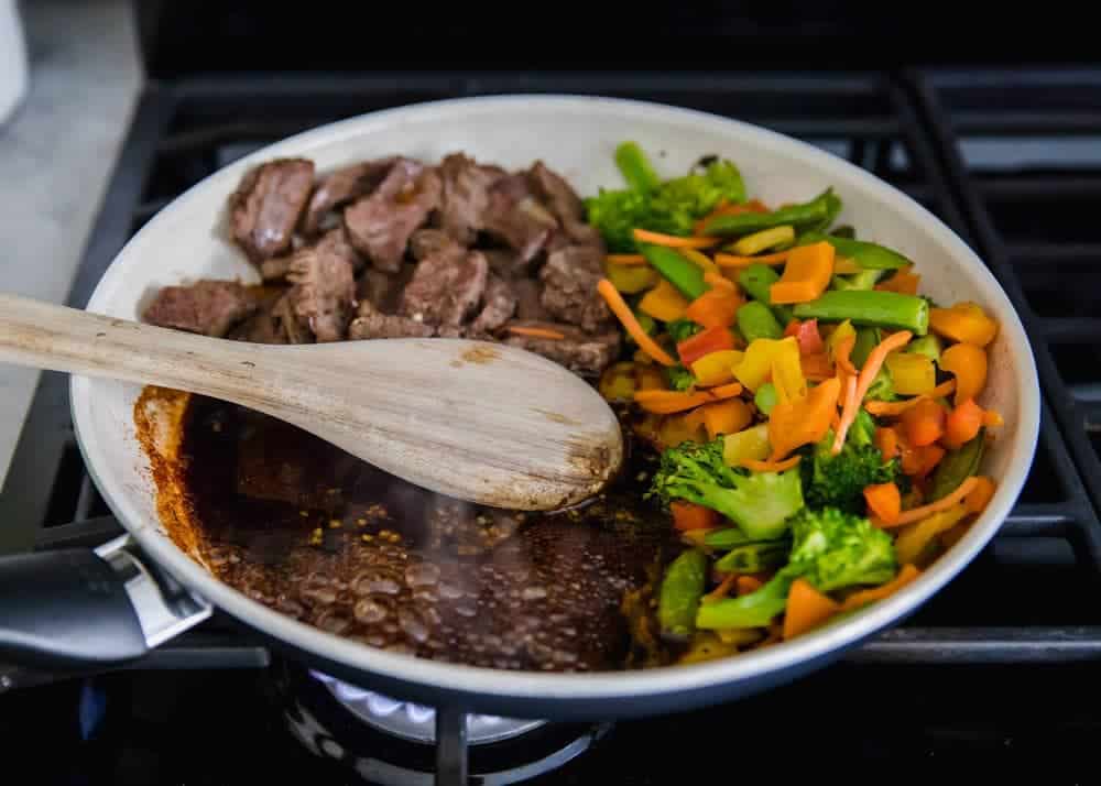 Cooking beef, veggies and sauce in pan for beef ramen.