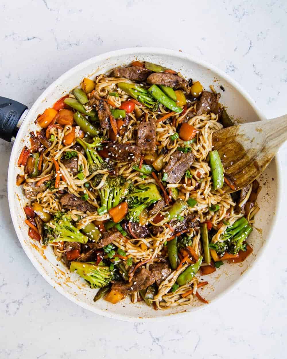 Beef ramen recipe in pan with wooden spoon.