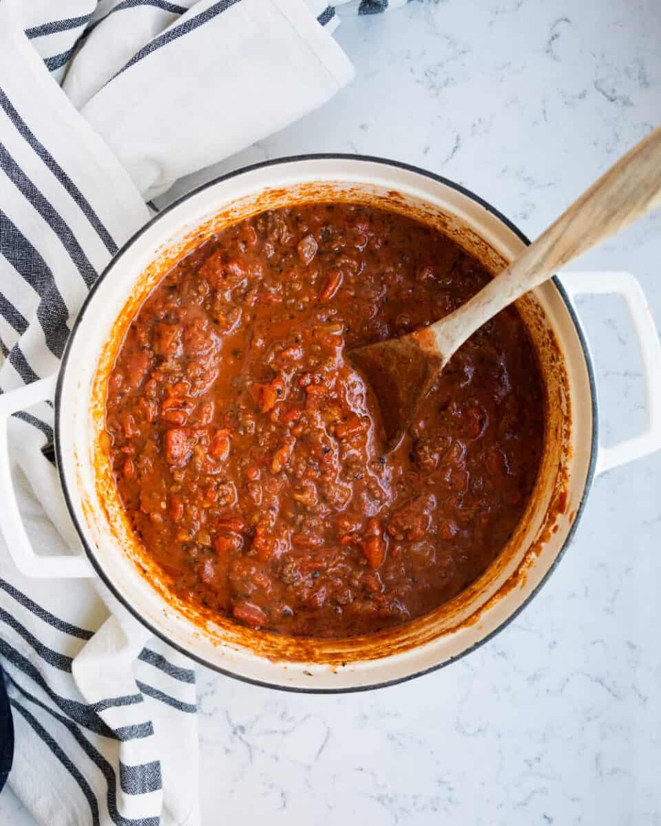 bolognese sauce in large pot with wooden spoon 