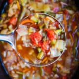 A close up of cabbage soup in a silver ladle