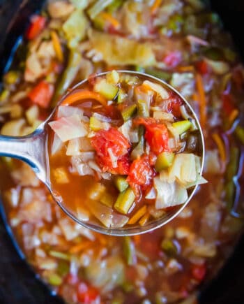 A close up of cabbage soup in a silver ladle