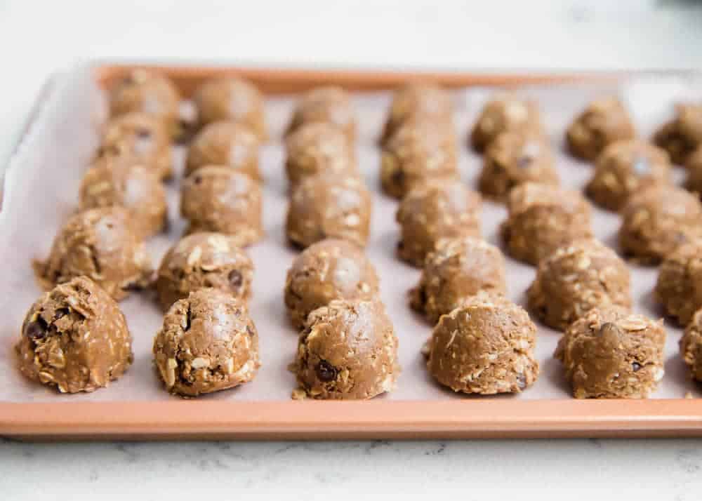 Protein balls on a parchment lined baking sheet.