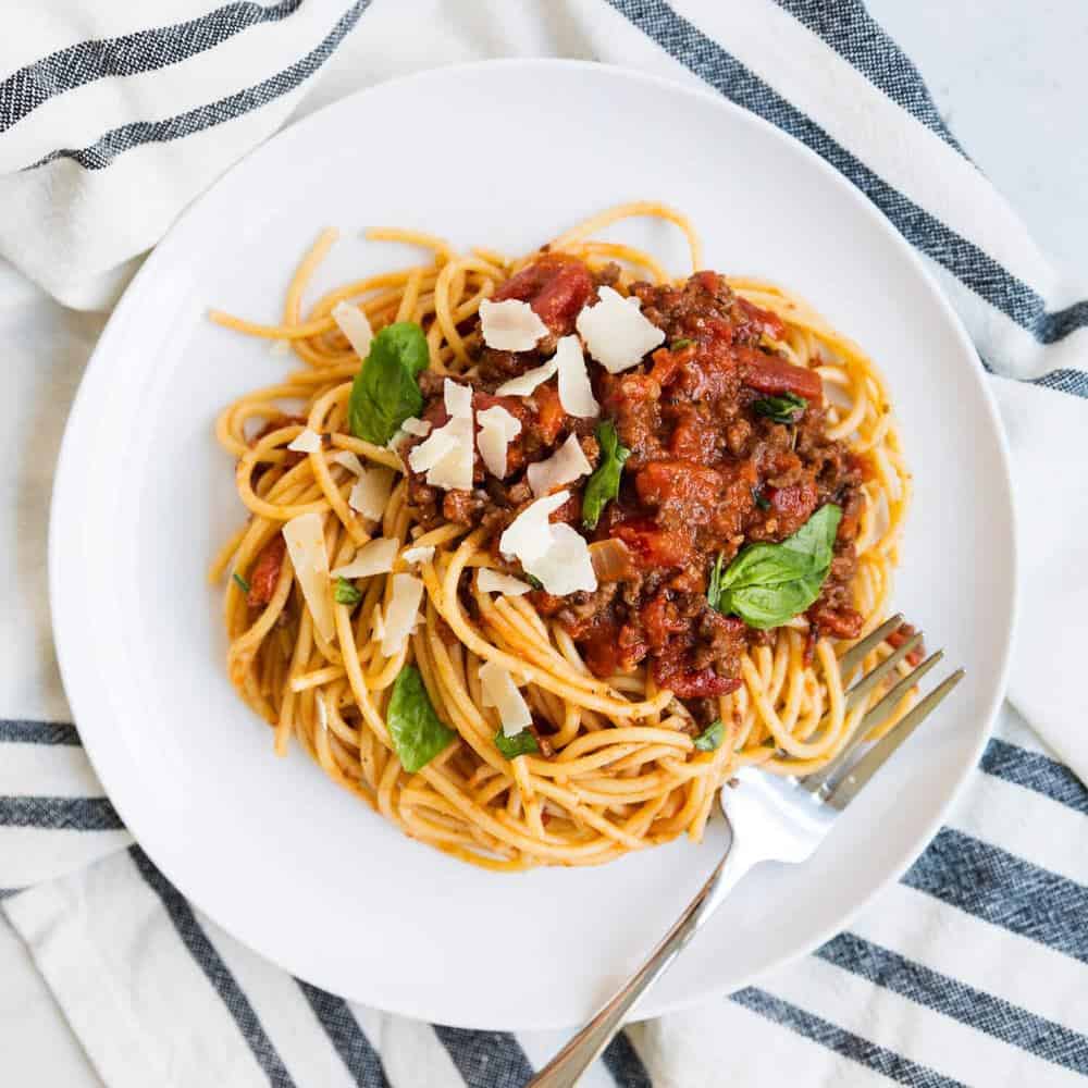 Spaghetti bolognese on white plate.