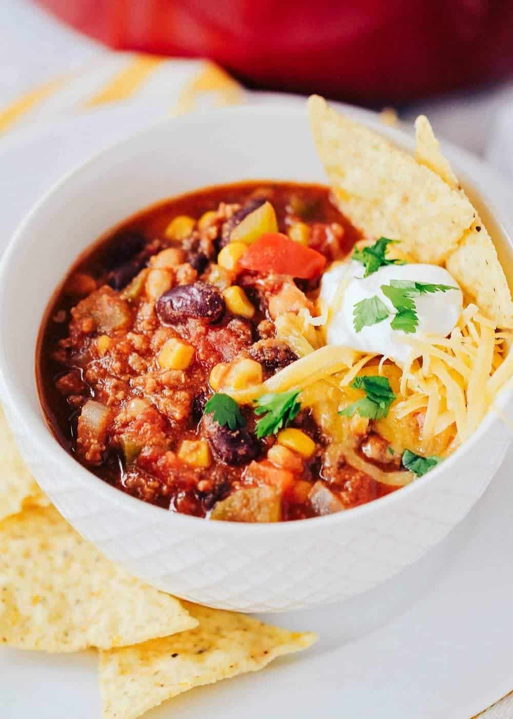 bowl of taco soup topped with cheese, sour cream, cilantro and tortilla chips 