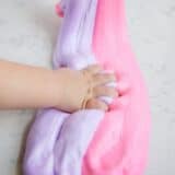 toddler's hand grabbing pink and purple fluffy slime