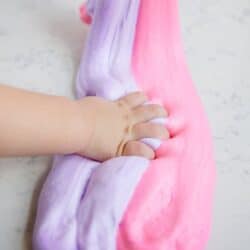 toddler's hand grabbing pink and purple fluffy slime