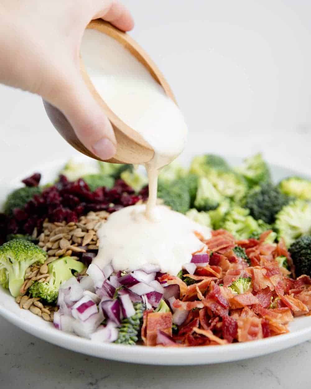 Pouring dressing over broccoli salad. 