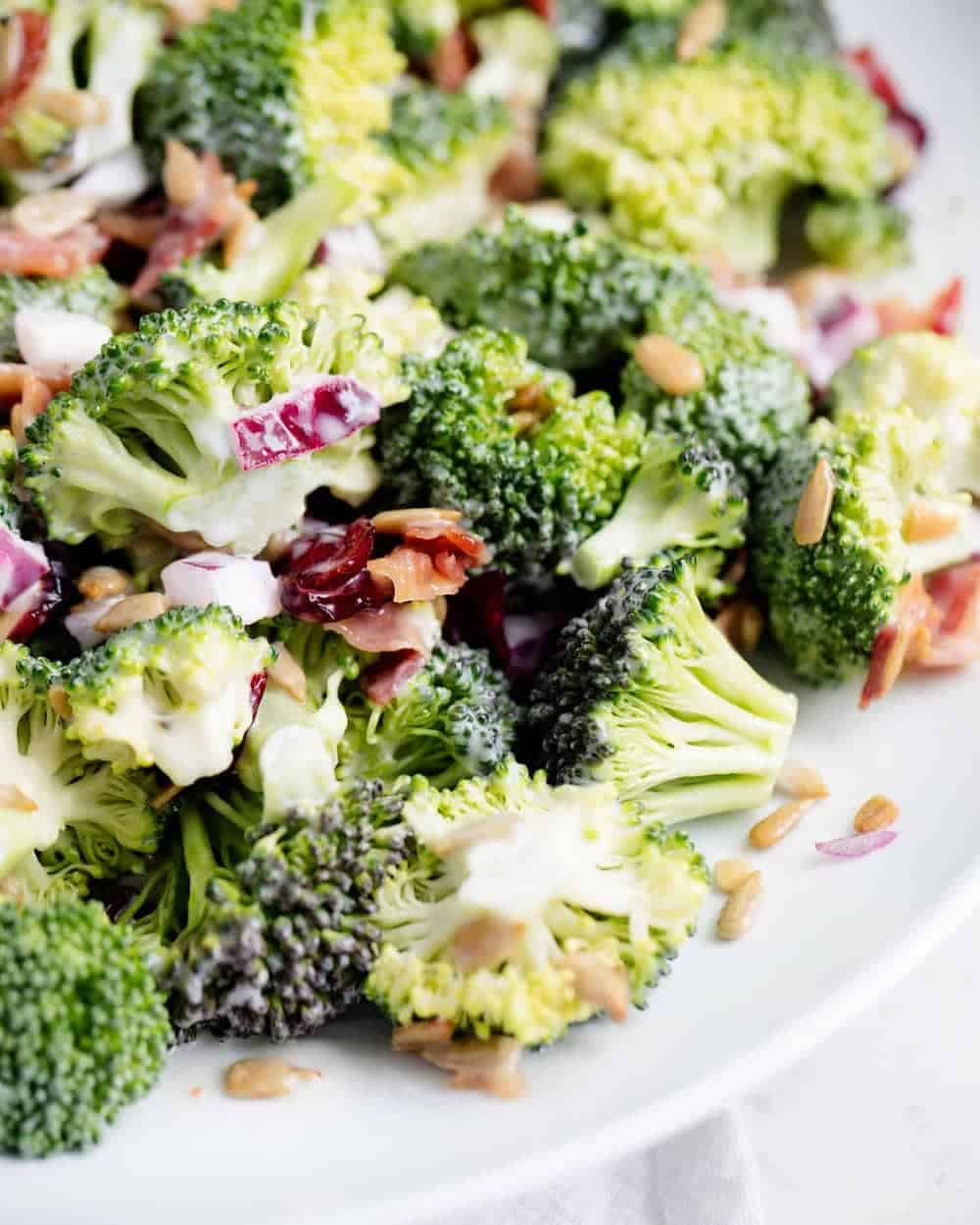 Close up of broccoli bacon salad on white plate.
