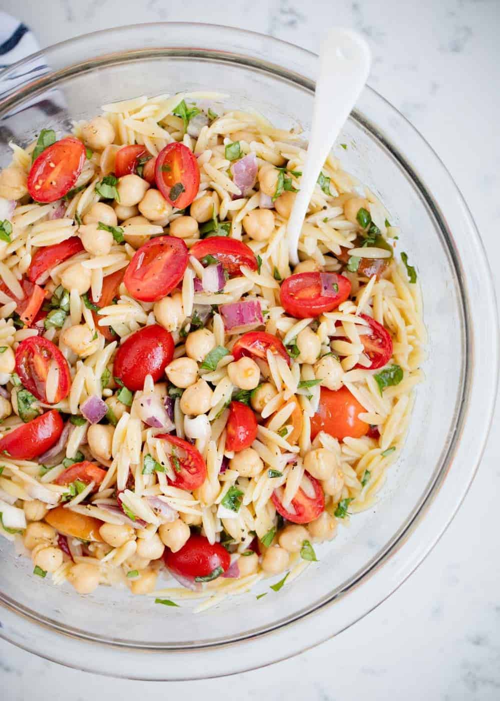 Orzo pasta salad in a bowl with a spoon.