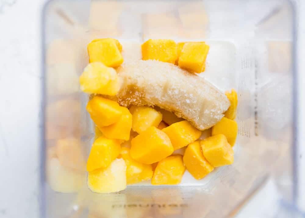 Frozen diced pineapple, mango and banana in a blender.