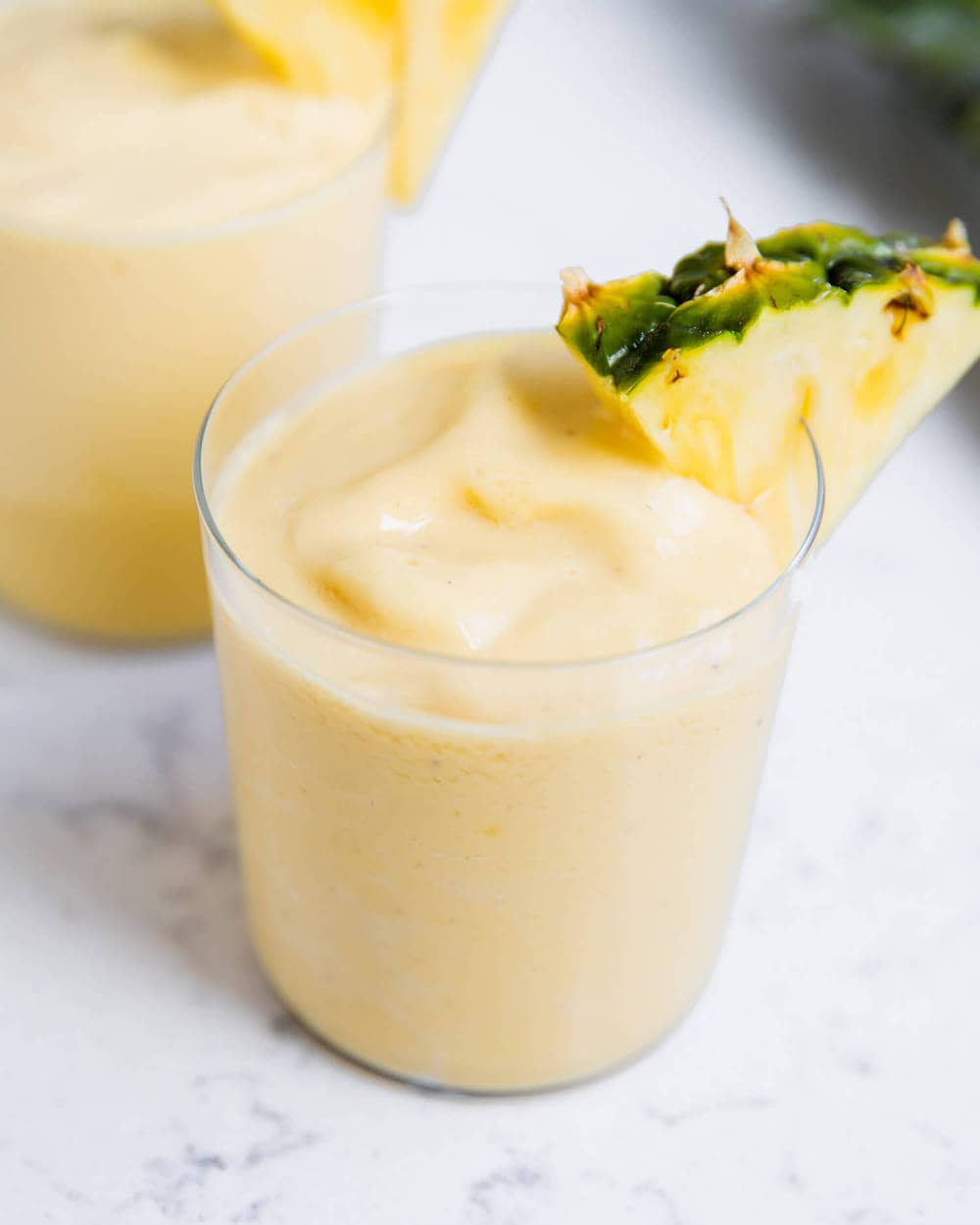 Close up of pineapple smoothie with fresh pineapple wedge.