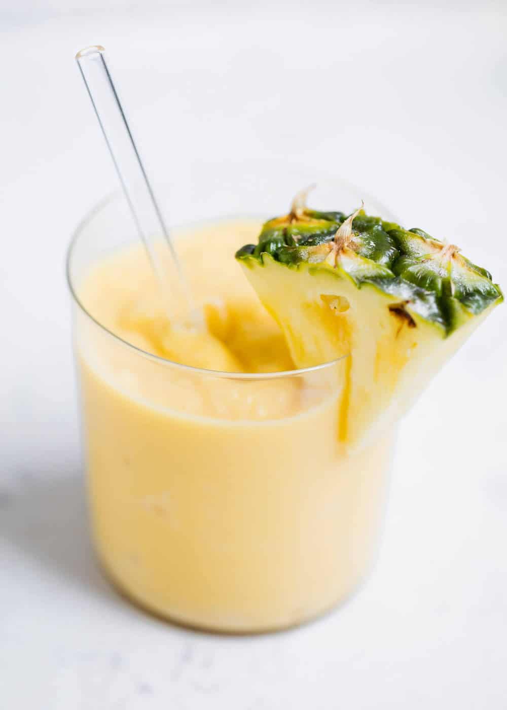 Pineapple smoothie in glass cup with straw.