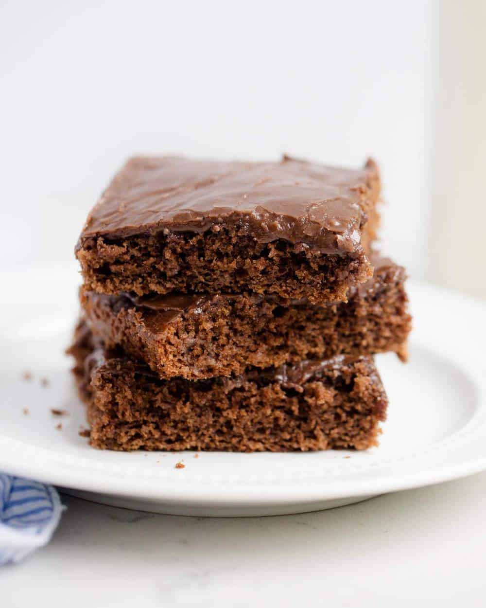 Stack of Texas sheet cake slices on a white plate.