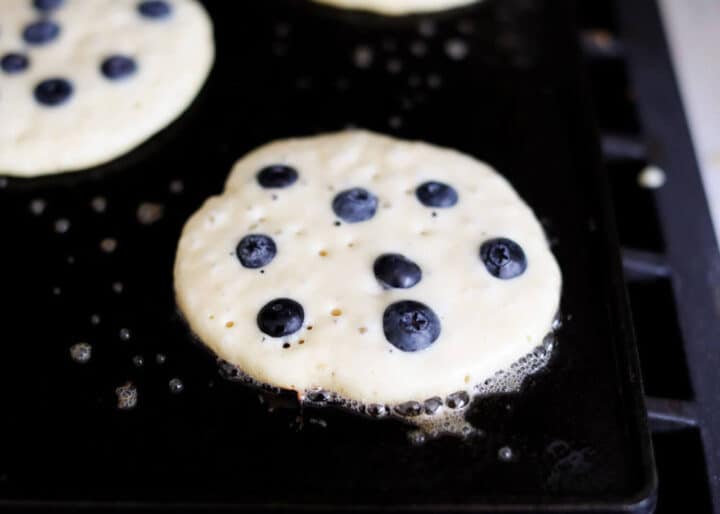 cooking ricotta pancakes with blueberries on griddle 