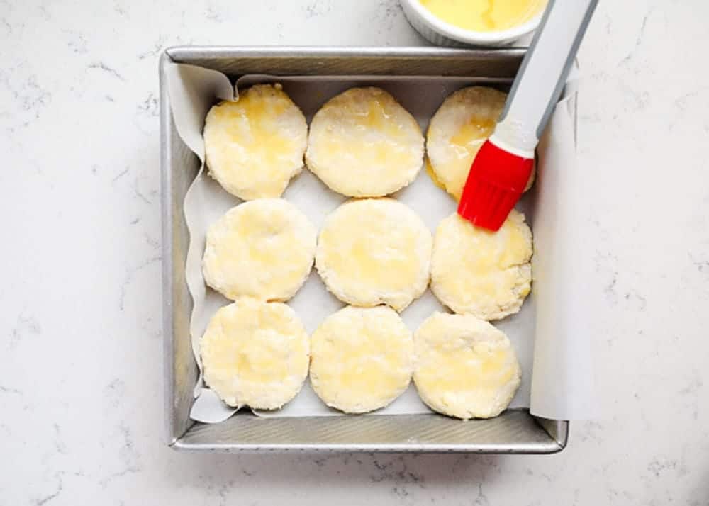 Brushing butter on biscuit dough.