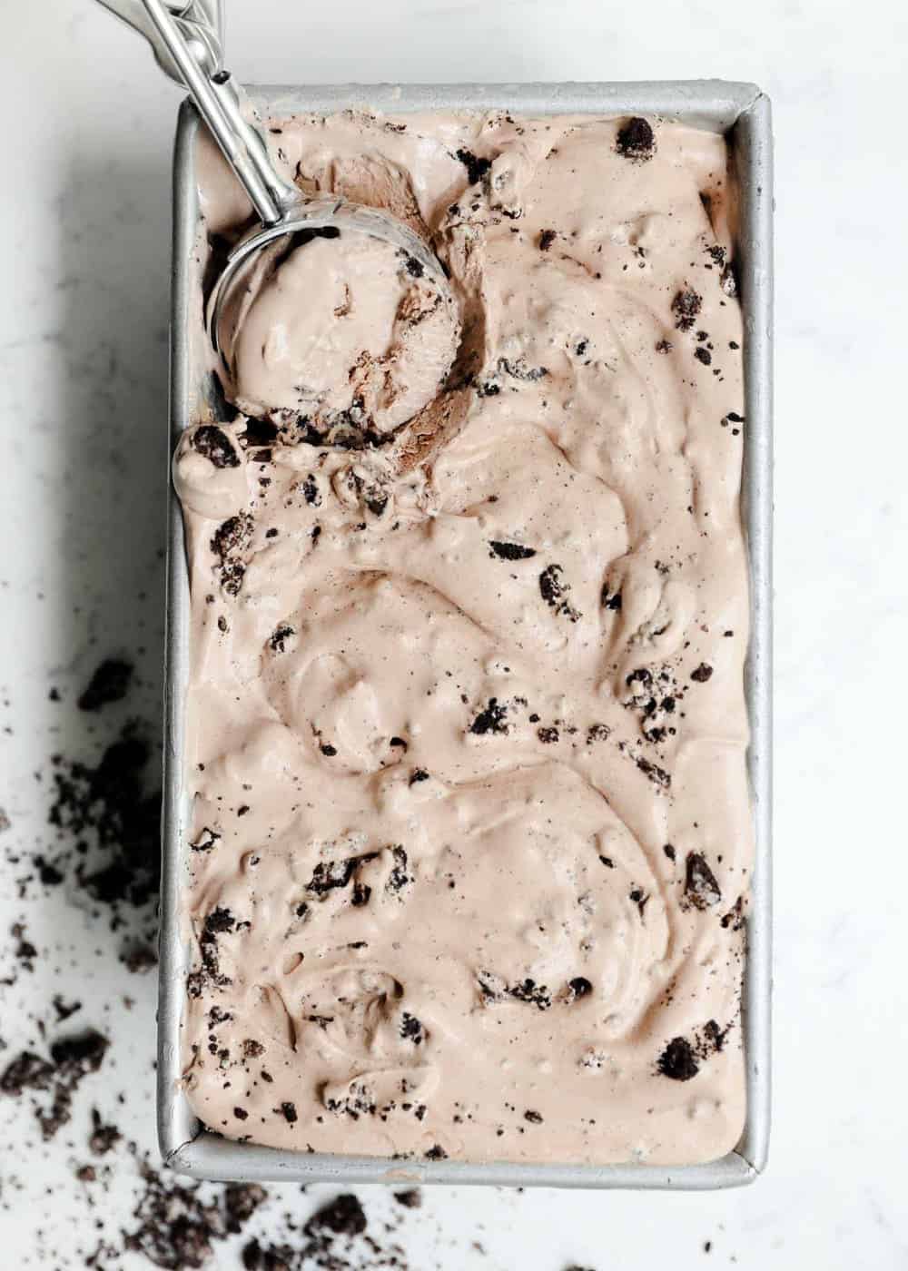 Scooping chocolate ice cream out of a loaf pan.