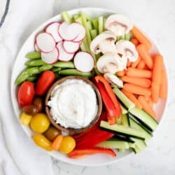 bowl of dill dip on a white plate with fresh veggies