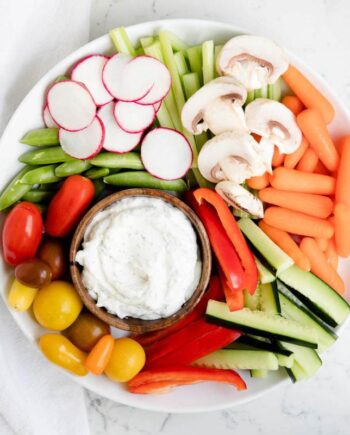 bowl of dill dip on a white plate with fresh veggies