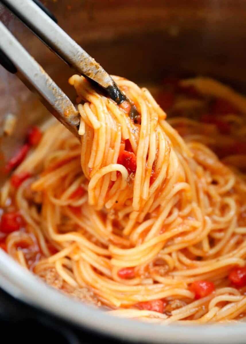 picking up spaghetti in instant pot with tongs 