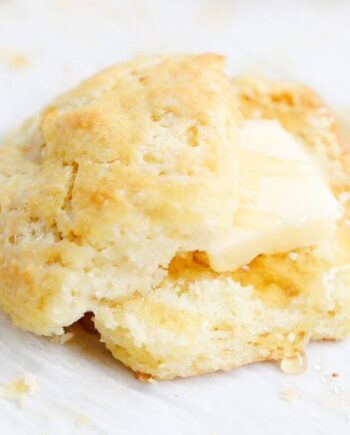 A sliced biscuit with butter and honey