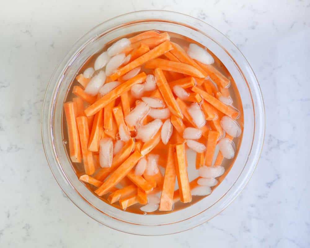 Sweet potato fries soaking in a bowl of ice water.