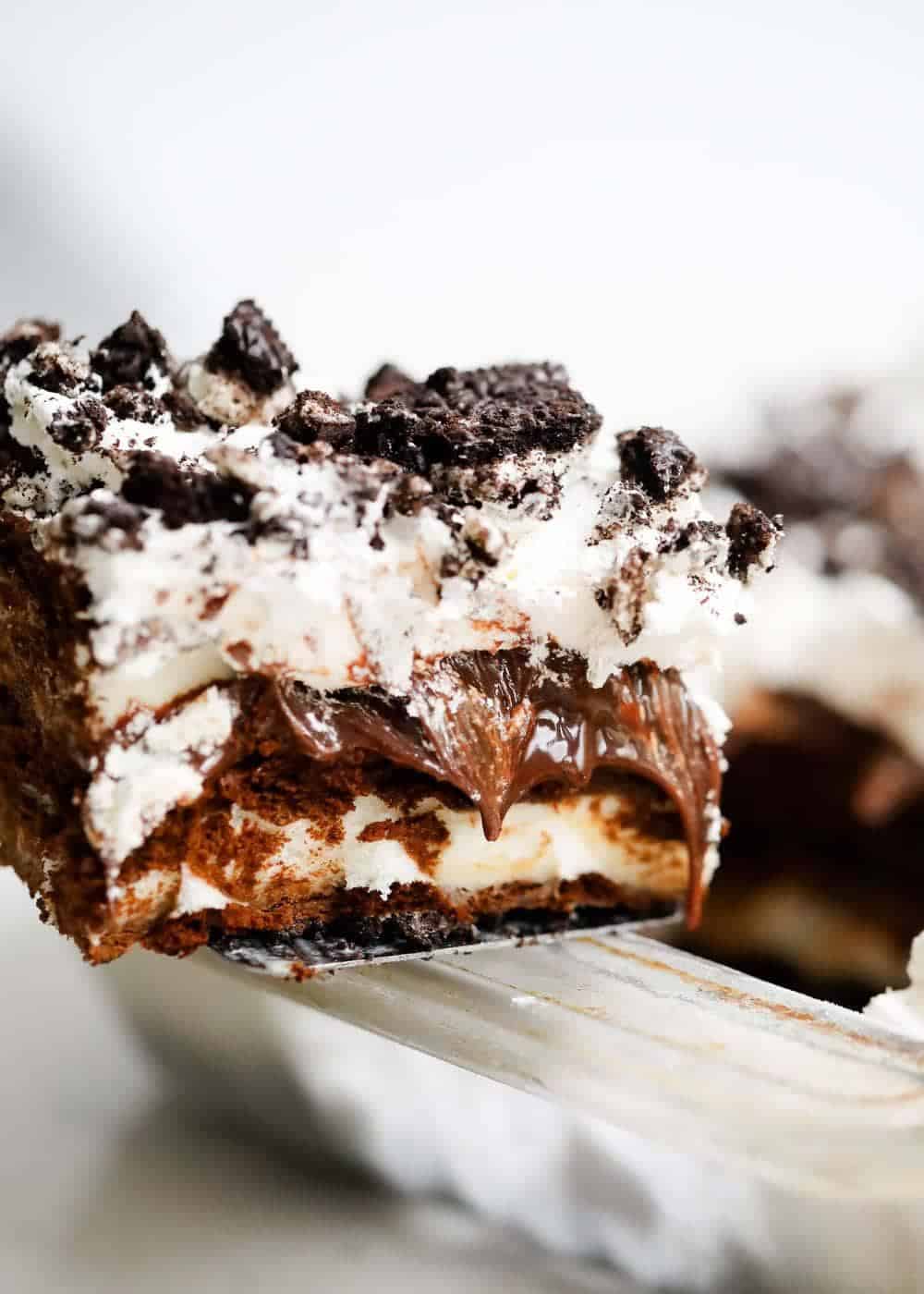 Piece of Oreo ice cream cake with hot fudge oozing out.