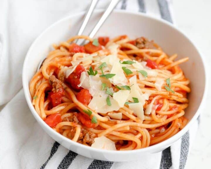 bowl of instant pot spaghetti topped with parmesan flakes and fresh basil 